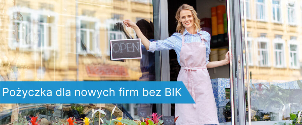 Kobieta w fartuchu stoi w drzwiach nowo otwartego sklepu z tabliczką OPEN